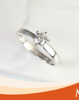 A silver solitaire engagement ring with a round-cut diamond set in a six-prong setting